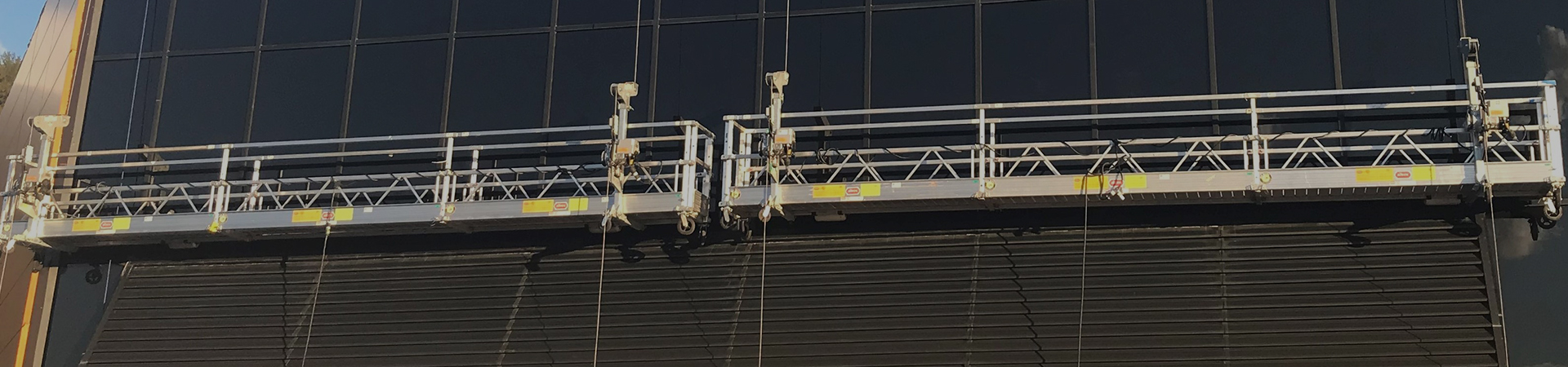 workers outside on elevated swing stage scaffolding platform