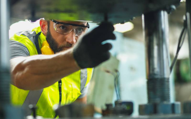 Construction worker performing maintenance on equipment at an industrial plant